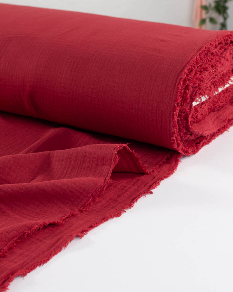 Bolt of red cotton double gauze fabric on a white background