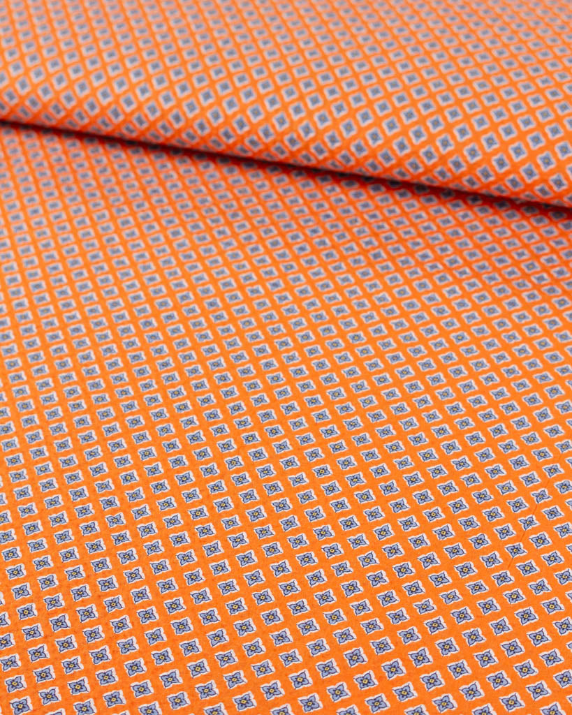 Roll of mango orange cotton seersucker fabric with small four-petal floral tile print