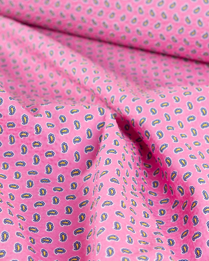 Bubblegum pink cotton seersucker fabric with a blue and yellow tiny paisley print