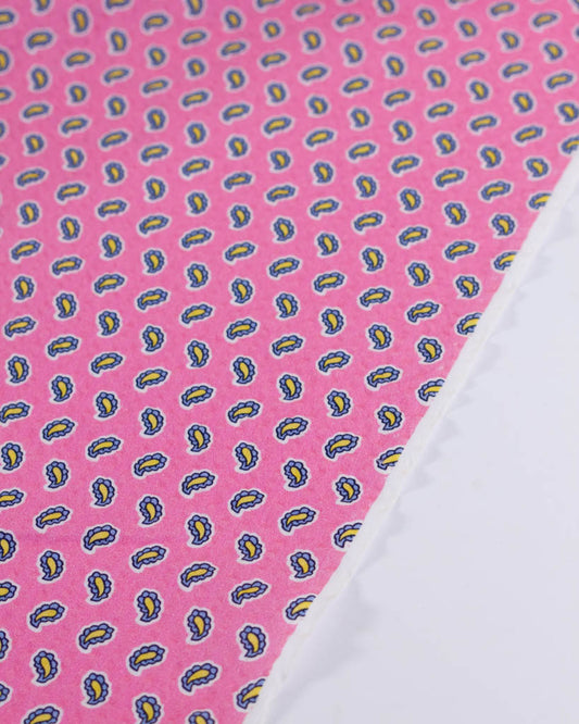 Selvedge edge of 100% cotton seersucker fabric in bubblegum pink with a tiny blue & yellow paisley print