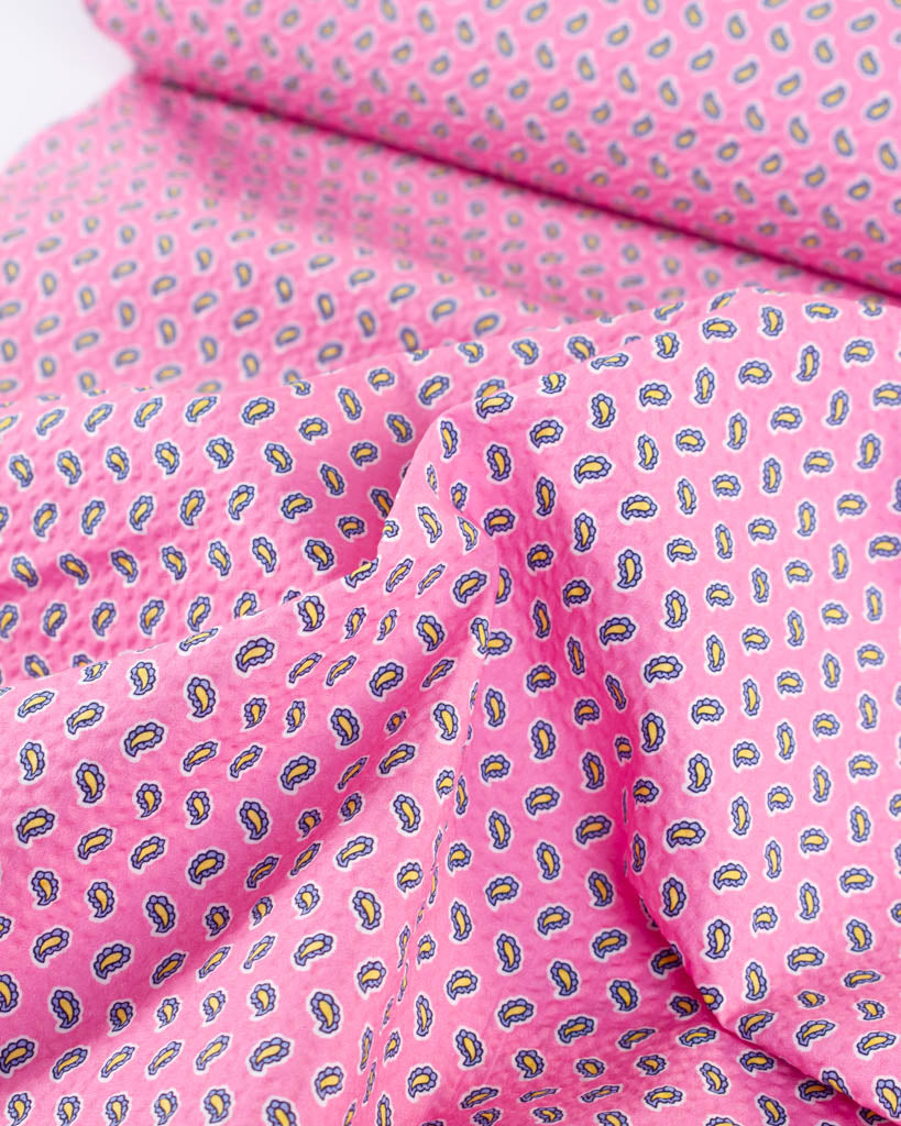 Close-up of pure cotton seersucker fabric in bubblegum pink with a tiny paisley print