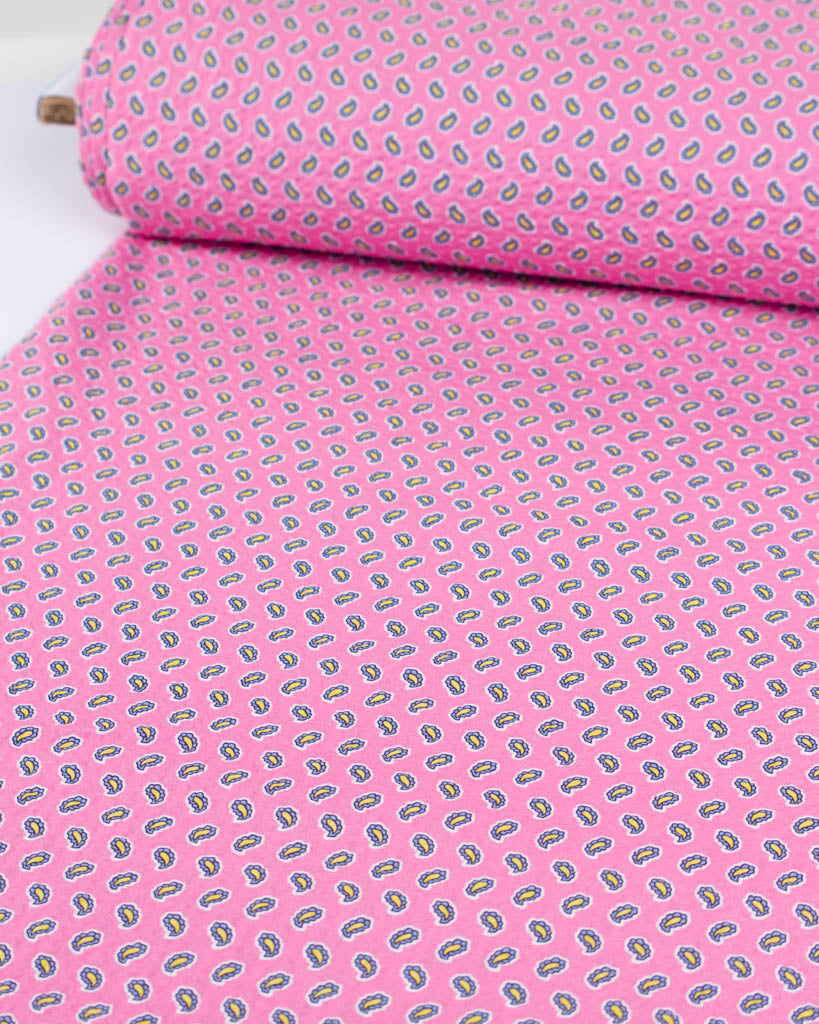 Roll of bubblegum pink pure cotton seersucker fabric with a tiny paisley print in blue & yellow