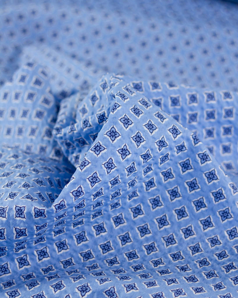Close-up of sky blue seersucker fabric with a charming geometric flower print