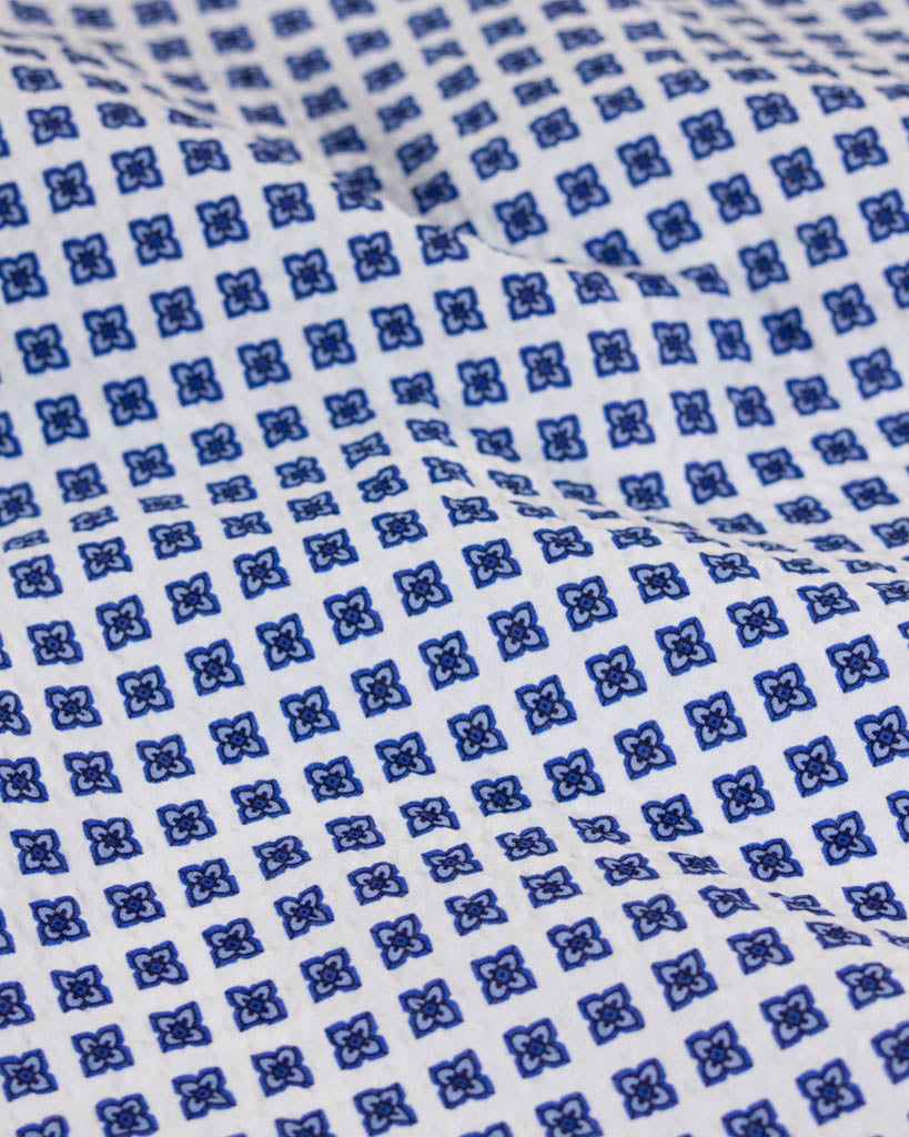 Textured white cotton fabric with an all-over four-petal geometric flower pattern