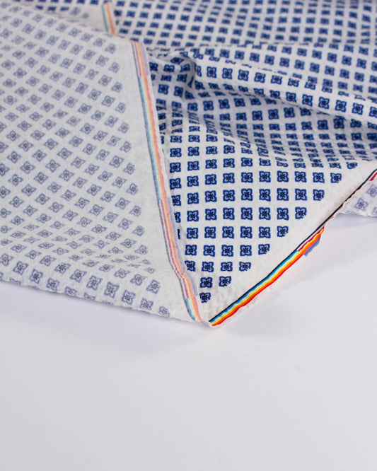 Crisp white cotton seersucker with a vintage-style geometric flower design and puckered texture