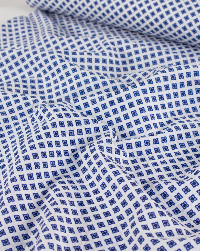 White cotton seersucker fabric with a delicate forget-me-not tile print