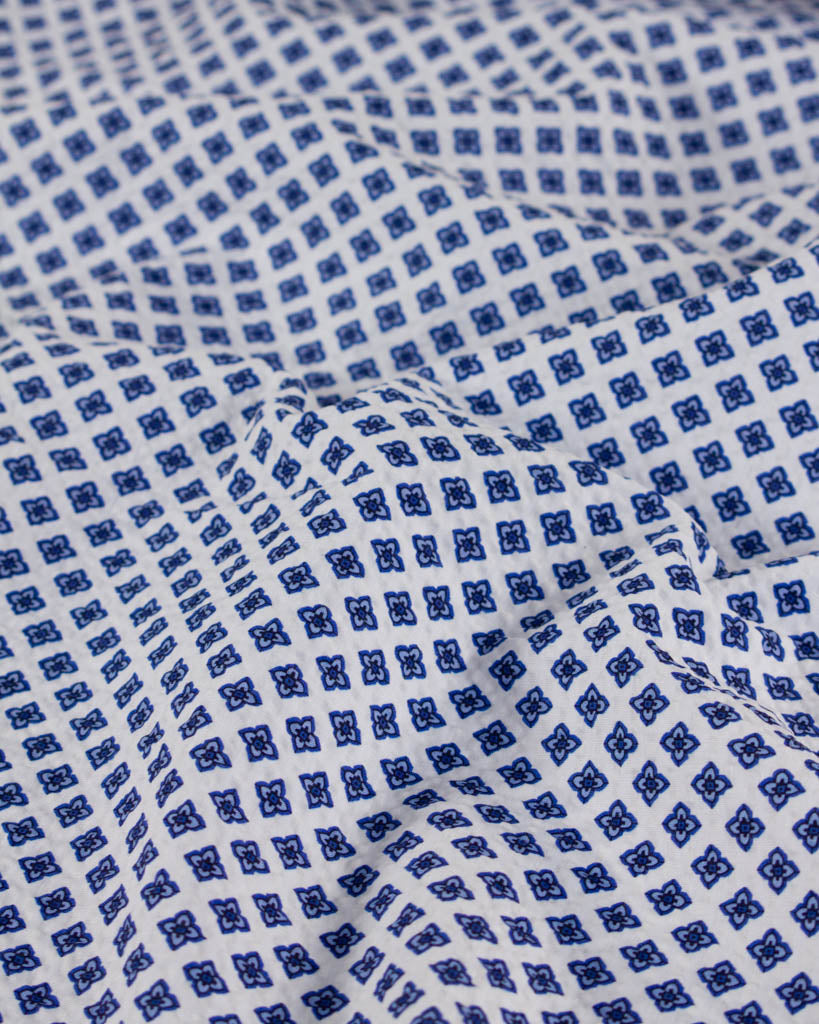 Close-up of white seersucker fabric showing a delicate tiled floral print