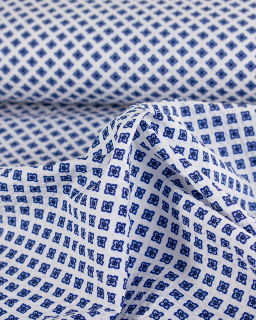 Lightweight white seersucker cotton featuring a small repeating blue floral design