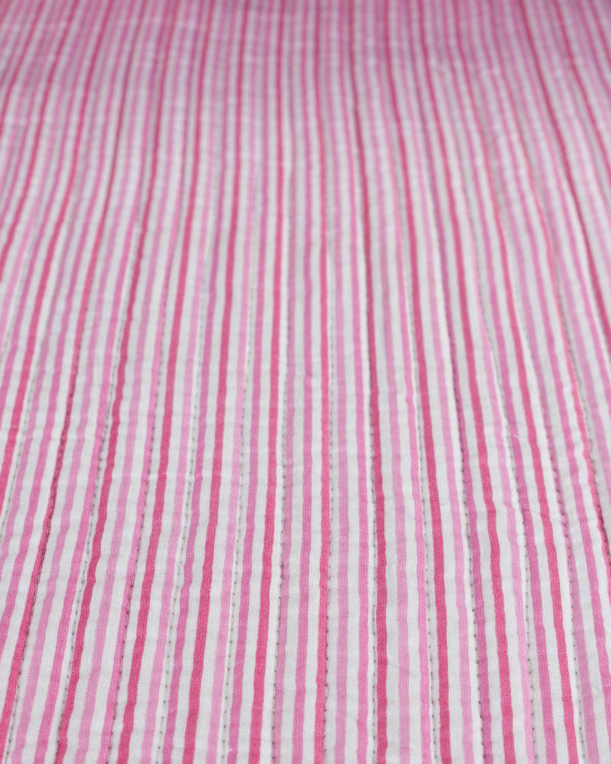 Close-up of pink and white striped quilted cotton fabric