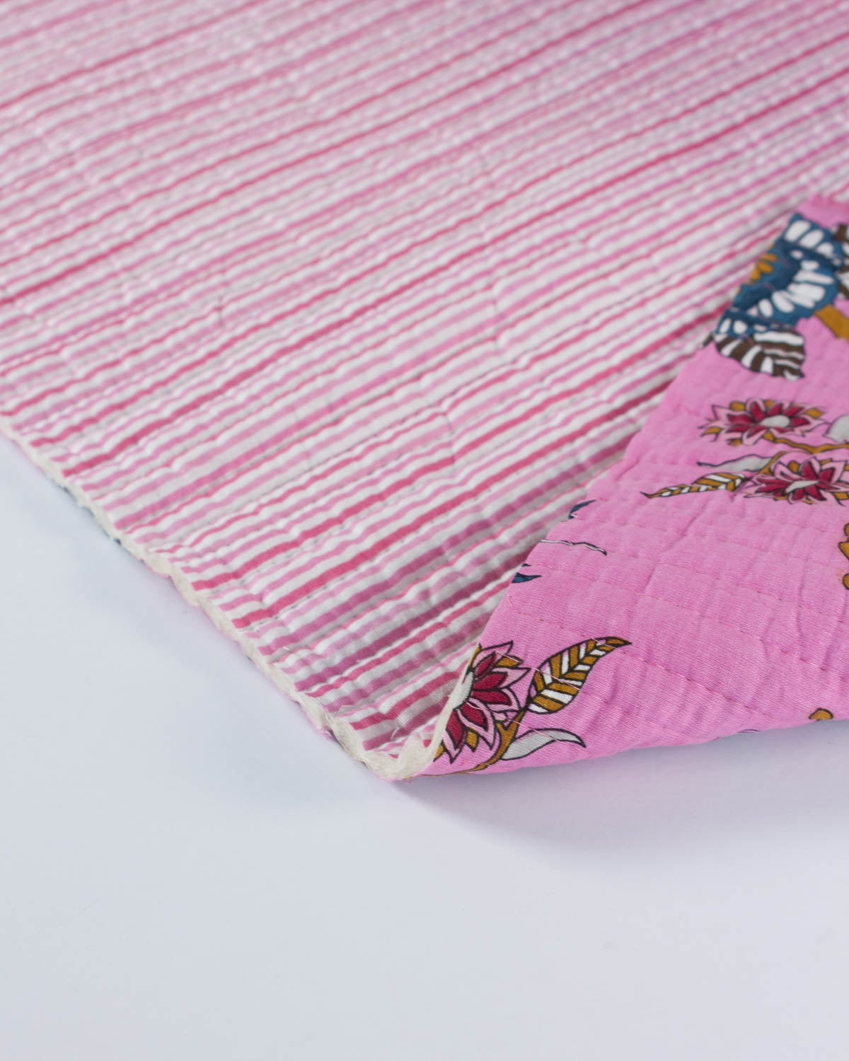 Close-up of pink cotton quilted fabric with floral pattern on a white background