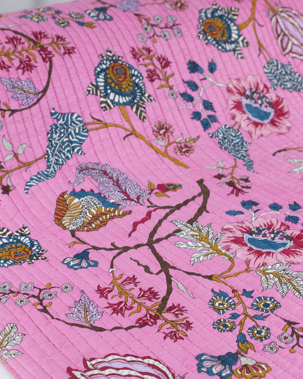 Floral patterned quilted cotton fabric on a pink background
