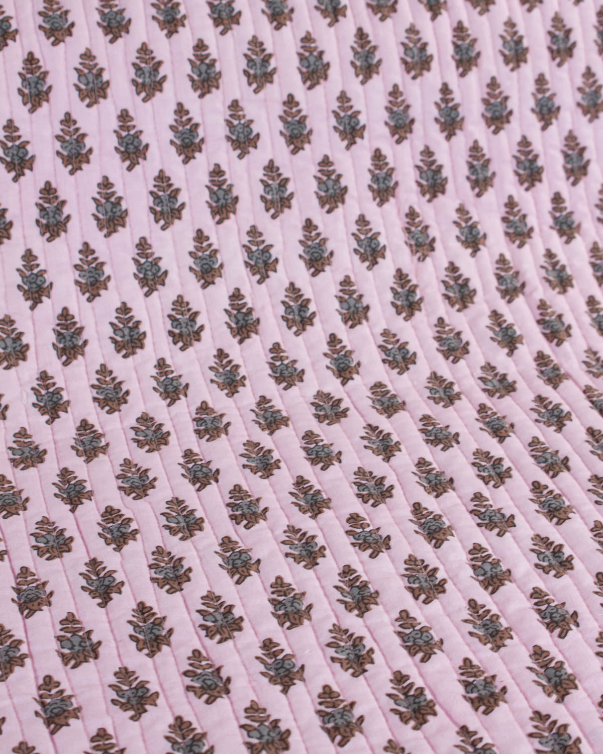 Patterned quilted cotton fabric with floral design on a pink background