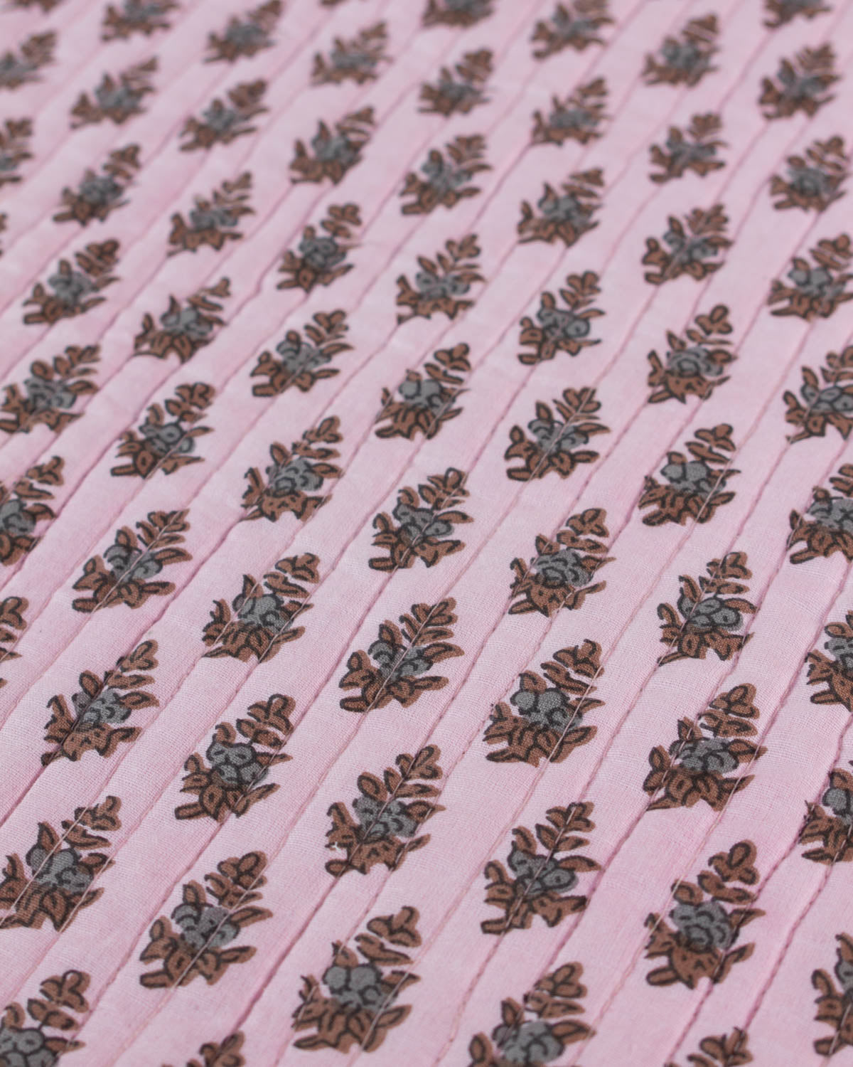 Patterned quilted cotton fabric with floral design on a pink background