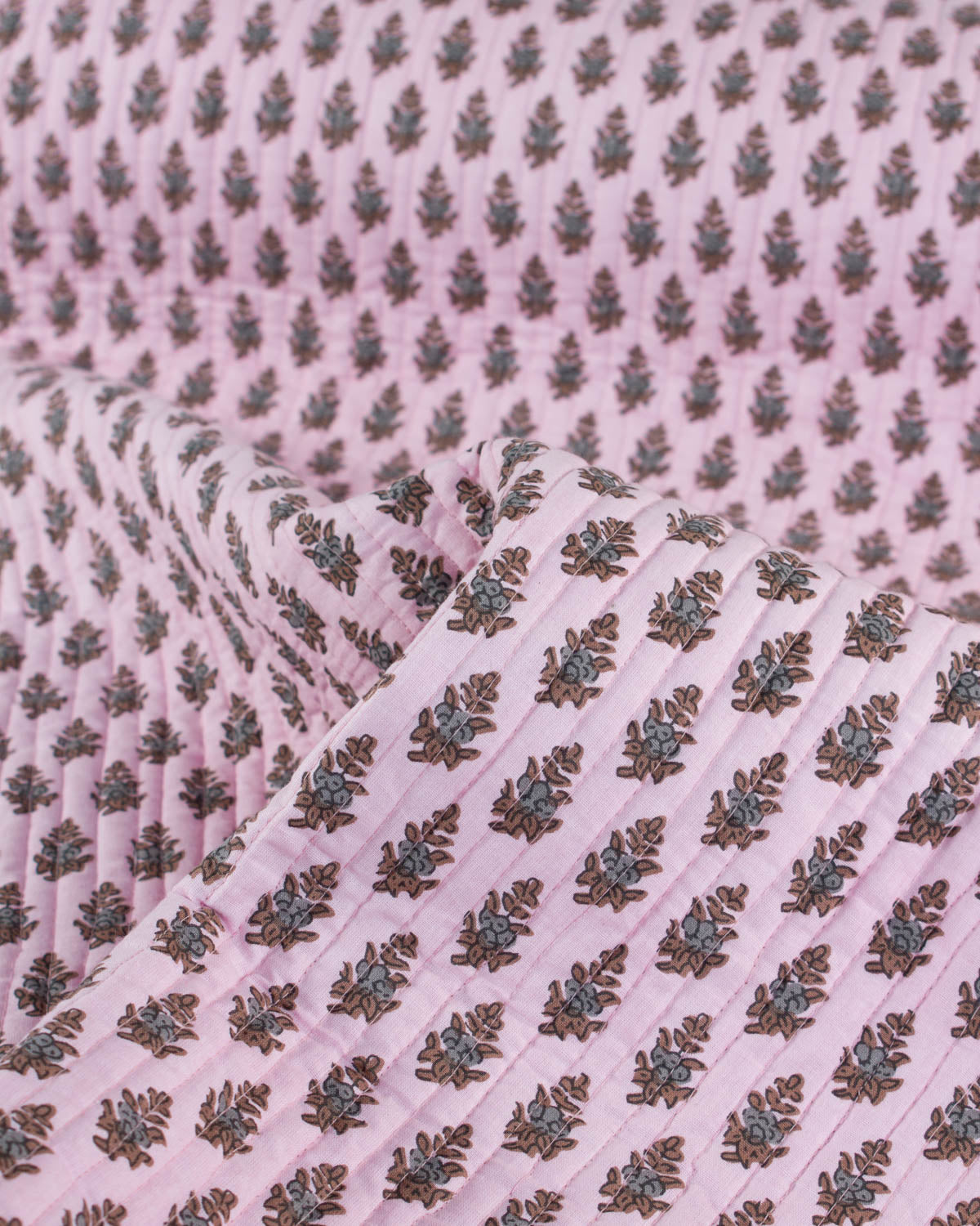 Pink quilted cotton fabric with a subtle pattern of leaves and flowers on a pink background
