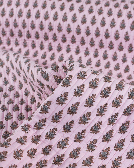 Pink quilted cotton fabric with a subtle pattern of leaves and flowers on a pink background