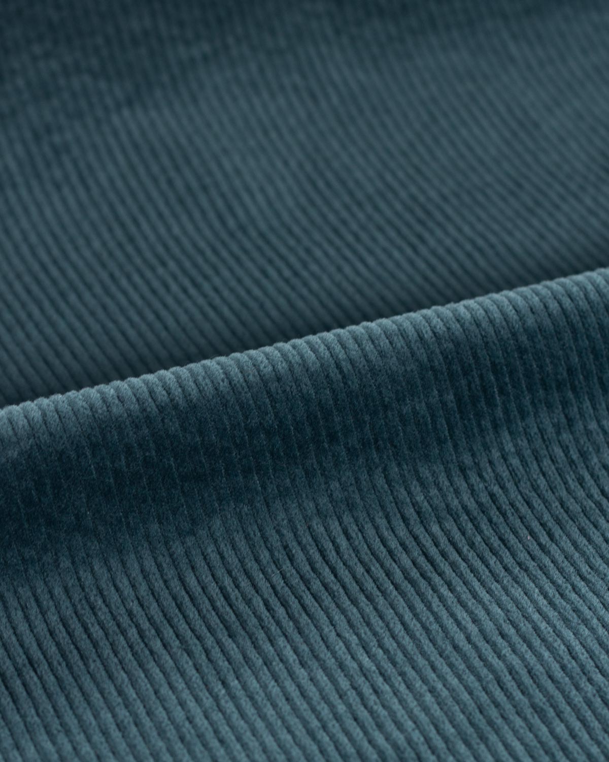 Close up of a dark teal cotton corduroy fabrics showing the defined wales.