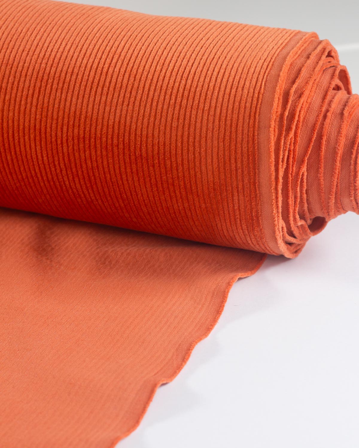 An orange cotton corduroy fabric roll.