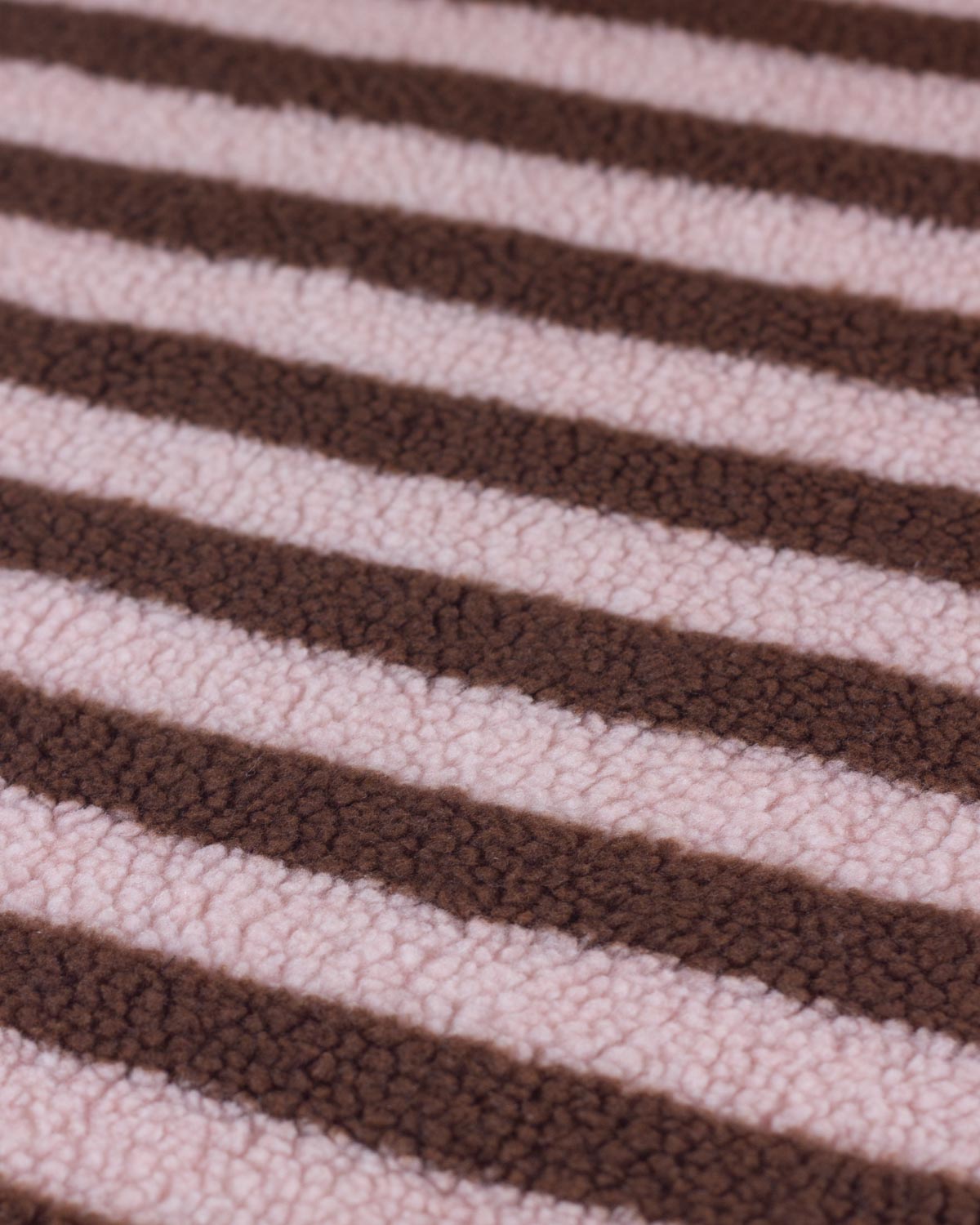 A close-up of a plush, textured fleece fabric with alternating horizontal stripes in dark brown and light pink.