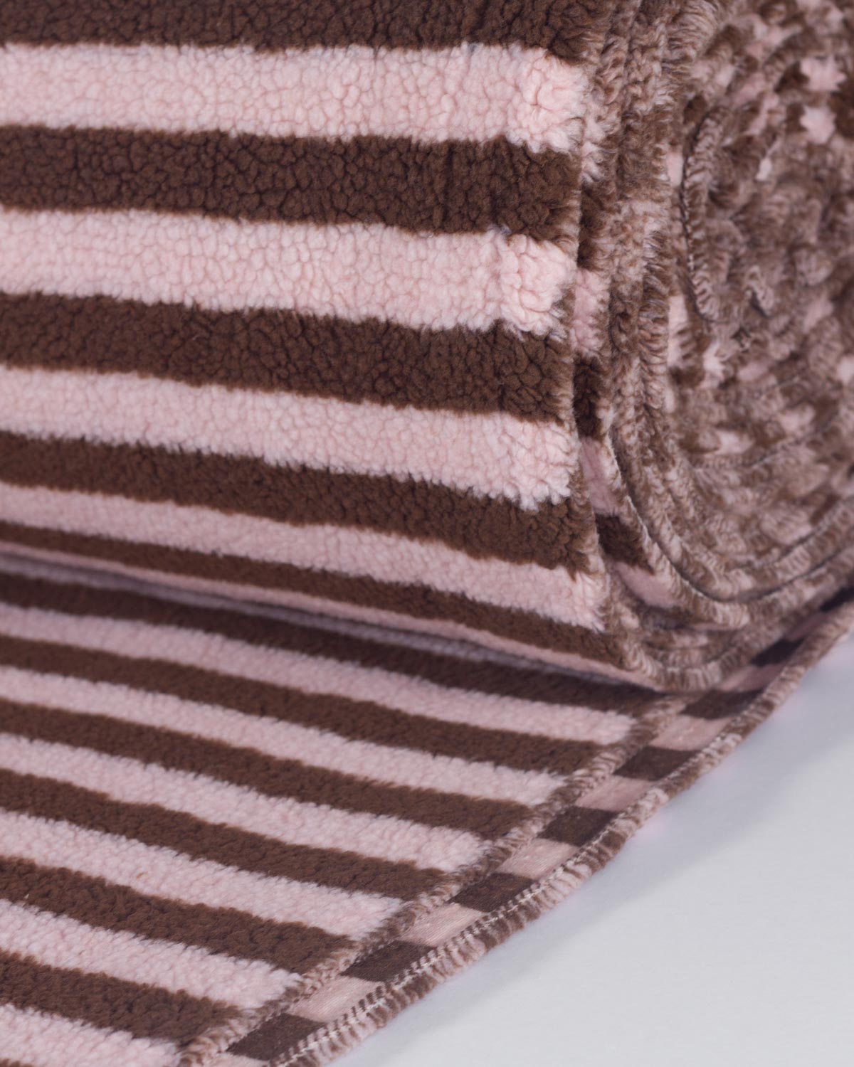 A close-up of a plush fleece fabric with horizontal brown and pale pink stripes, shown partially unrolled with a rolled edge revealing the soft texture.
