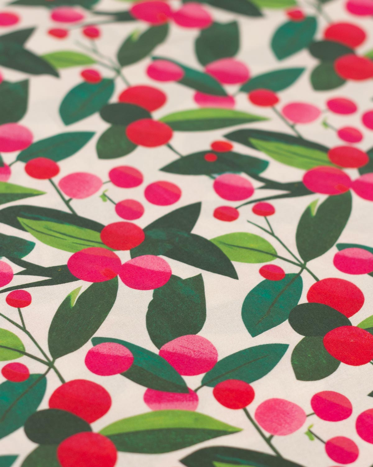 A close-up of a christmas cotton  fabric pattern featuring stylized red and pink berries with green leaves on a light cream background.