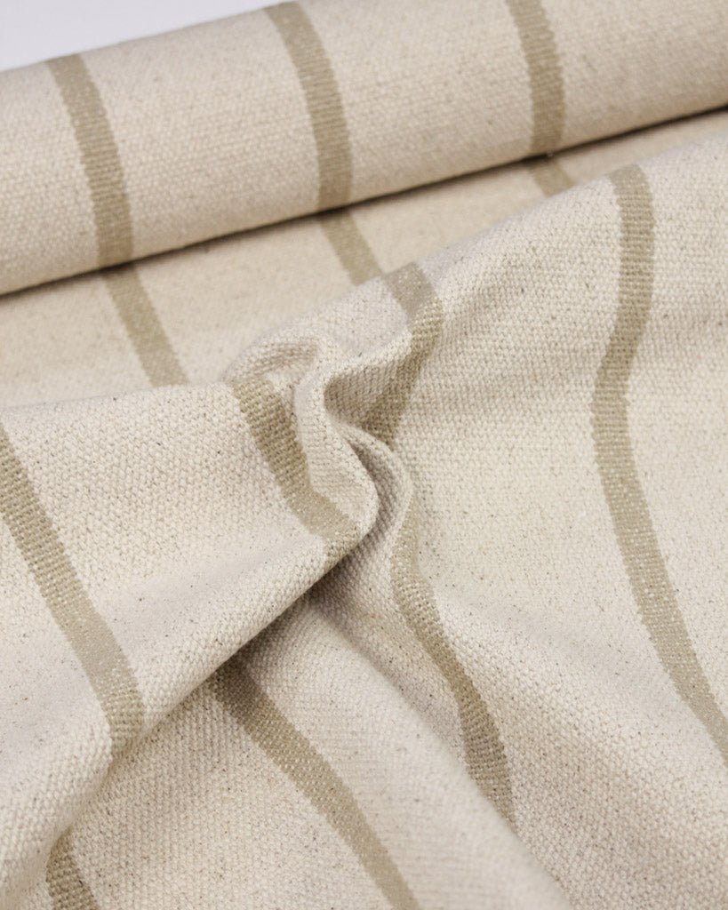 A close-up of a woven cotton upholstery fabric featuring a warm beige base with vertical taupe stripes.