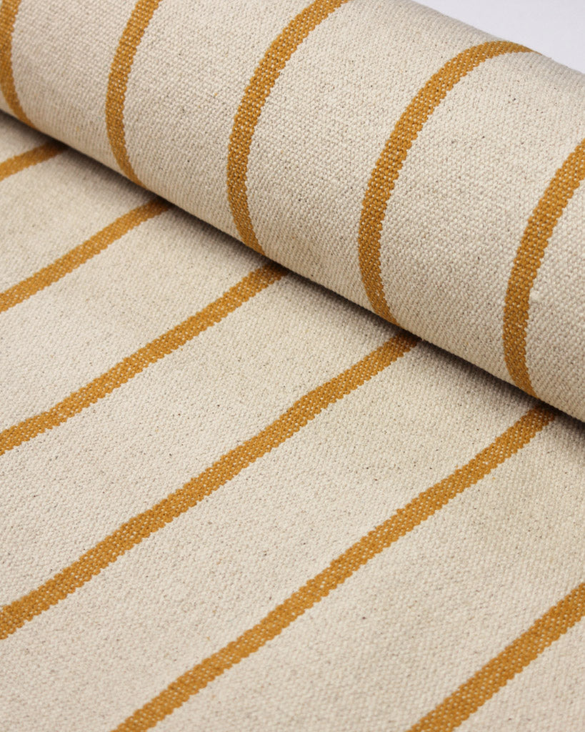 A close-up of a woven cotton upholstery fabric with a cream base and mustard yellow vertical stripes