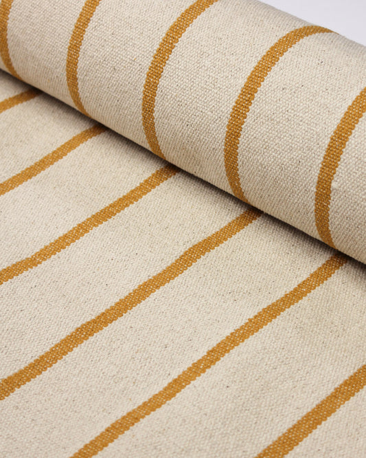 A close-up of a woven cotton upholstery fabric with a cream base and mustard yellow vertical stripes