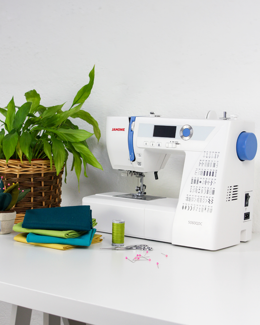 5060QDC Janome Sewing machine on a table with fabric and a plant in the background