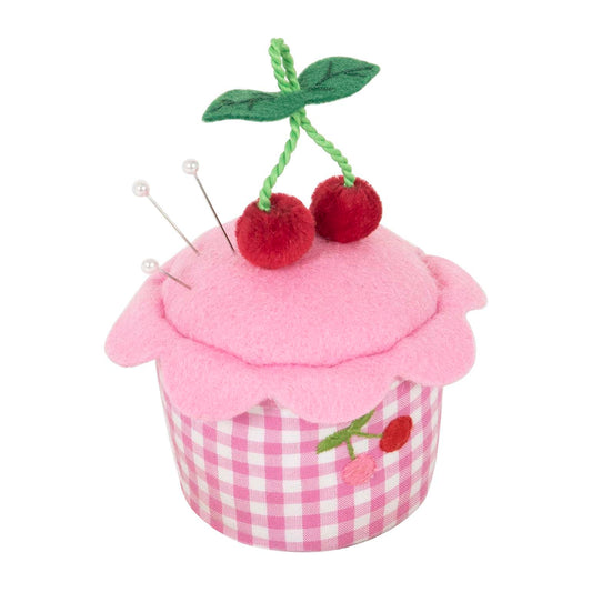 Pink cupcake-shaped pincushion with red cherries on a white background