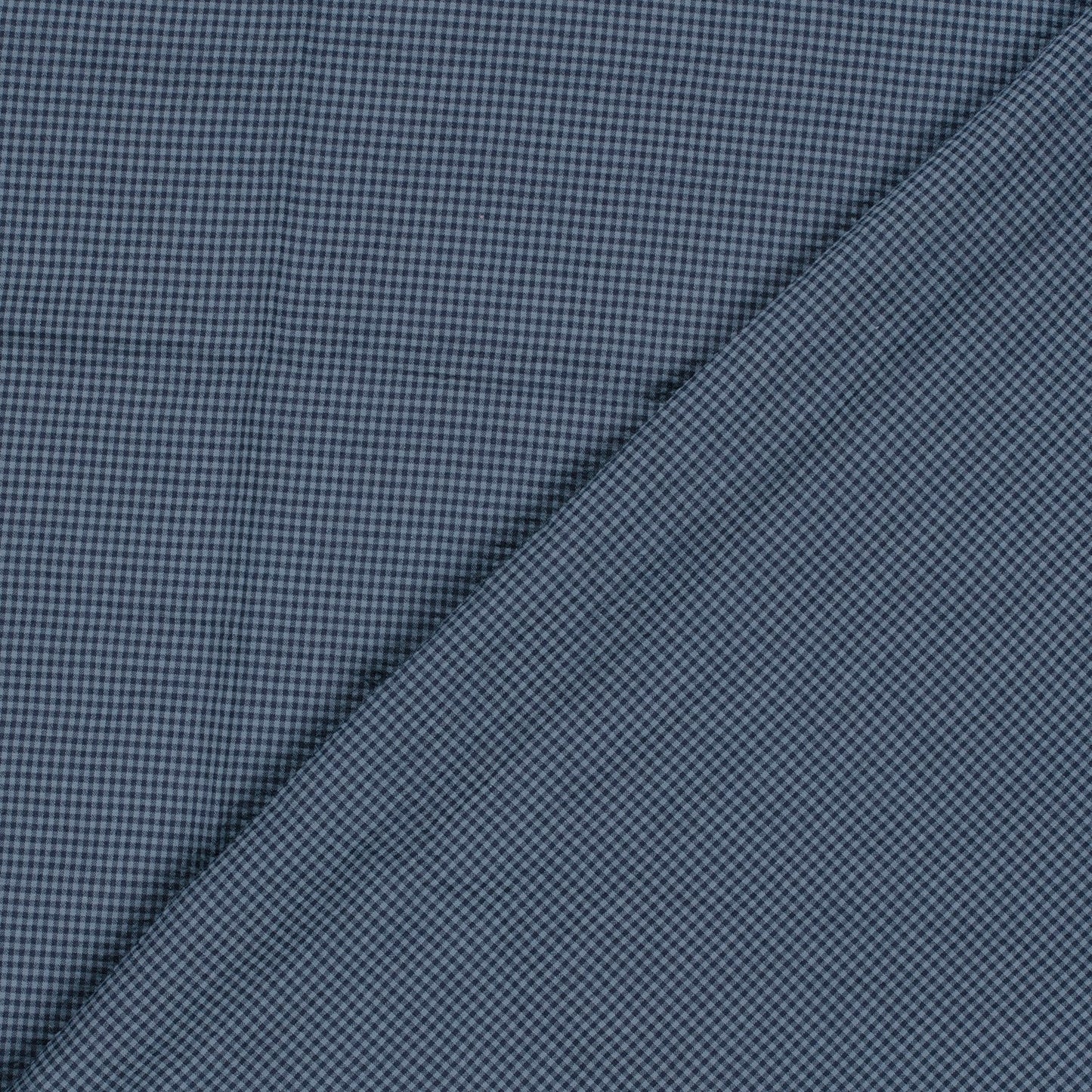 A close-up of a textured fabric with a fine micro-check pattern in navy blue and black, folded diagonally across the frame.
