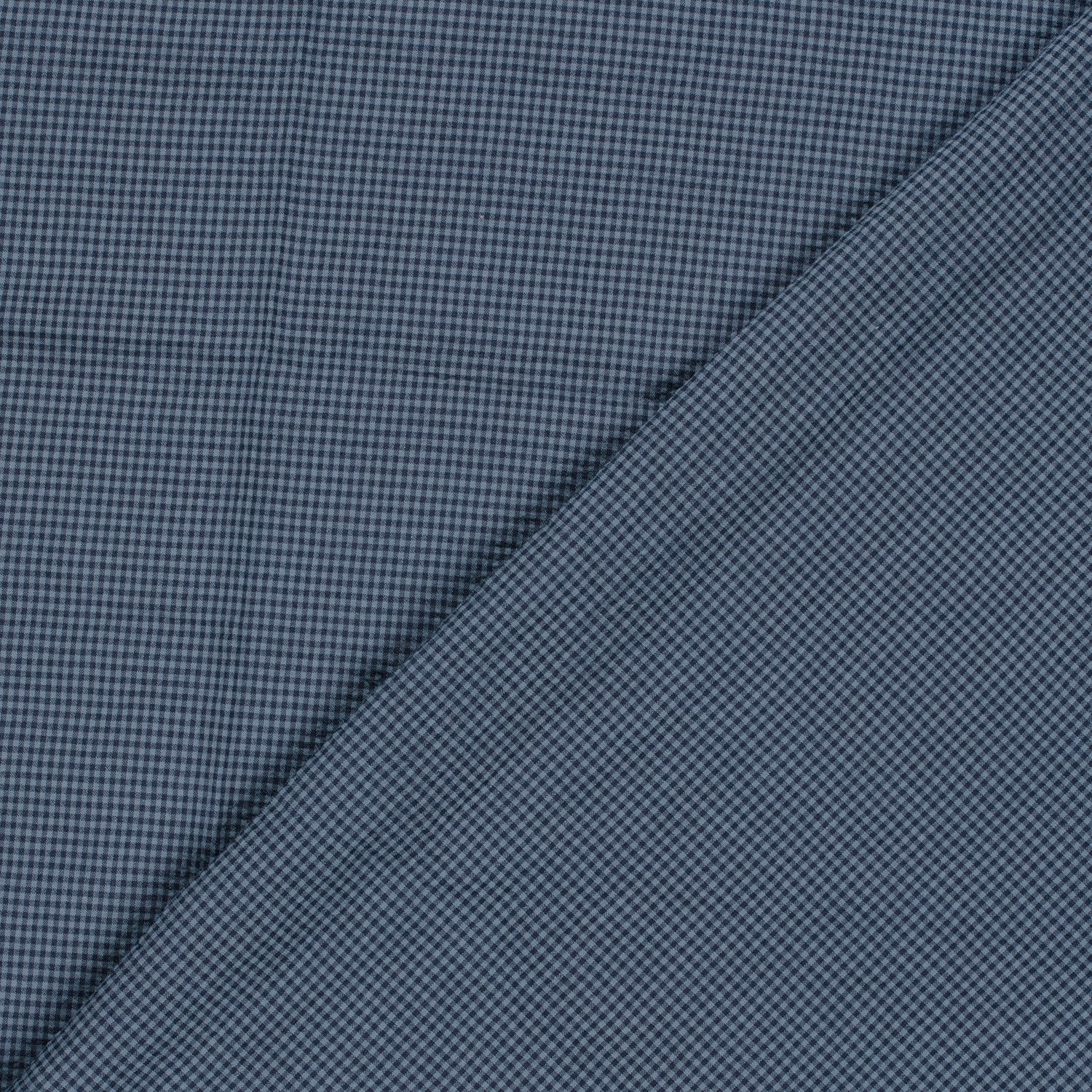 A close-up of a textured fabric with a fine micro-check pattern in navy blue and black, folded diagonally across the frame.