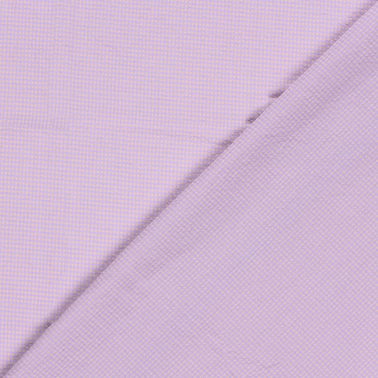 A close-up of a light lavender purple fabric with a fine micro-check pattern, folded diagonally across the frame.