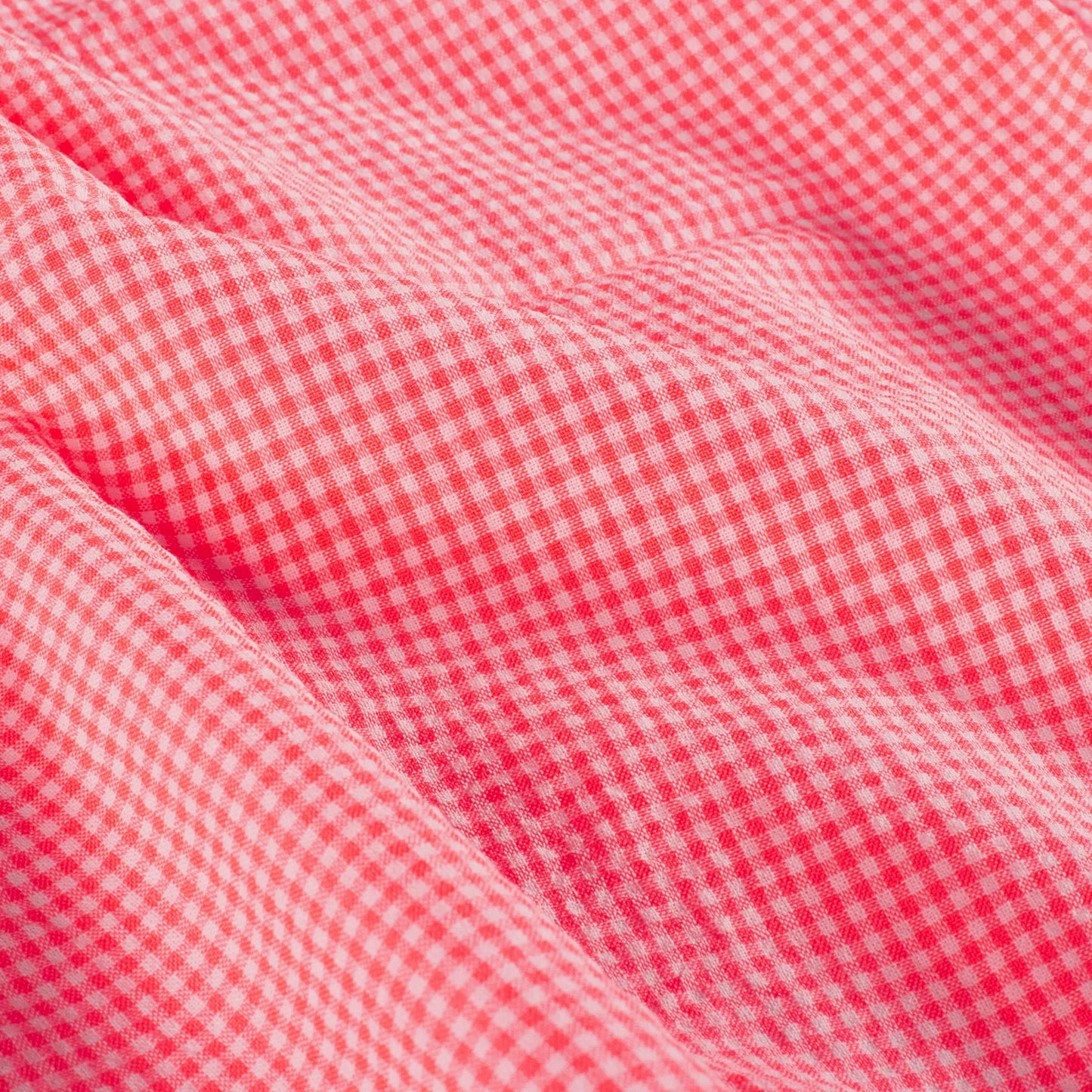 A close-up of red and white gingham fabric with soft folds showing the texture and pattern.