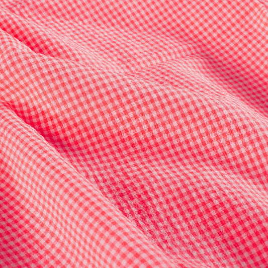 A close-up of red and white gingham fabric with soft folds showing the texture and pattern.