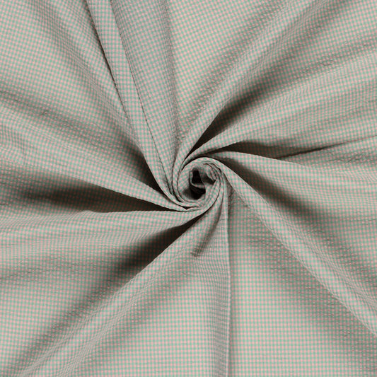 A close-up of a light gray and white gingham fabric, artistically swirled into a spiral pattern to show off its drape and texture.