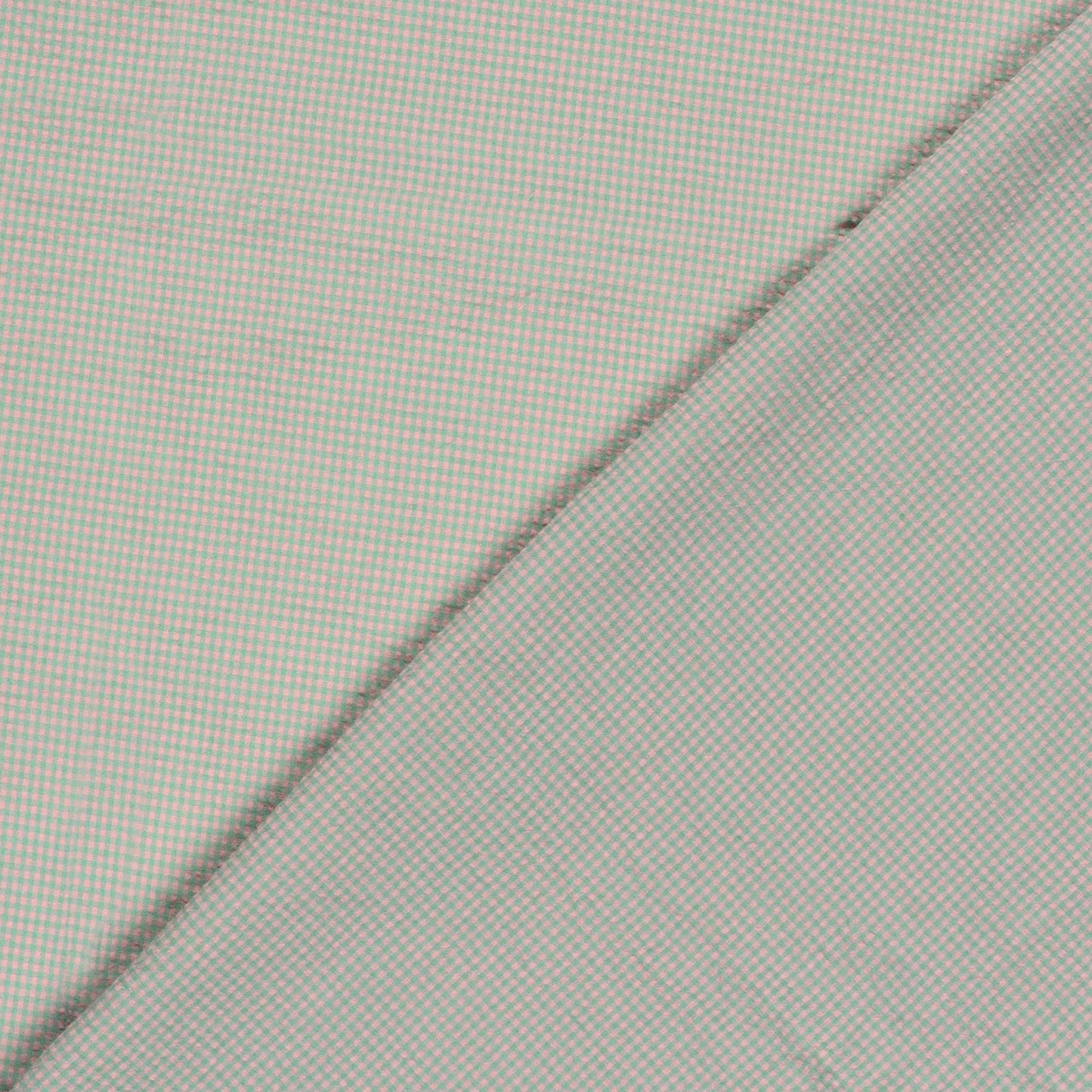 Close-up of a pink and green fabric with a fine micro-check pattern, folded diagonally across the frame.