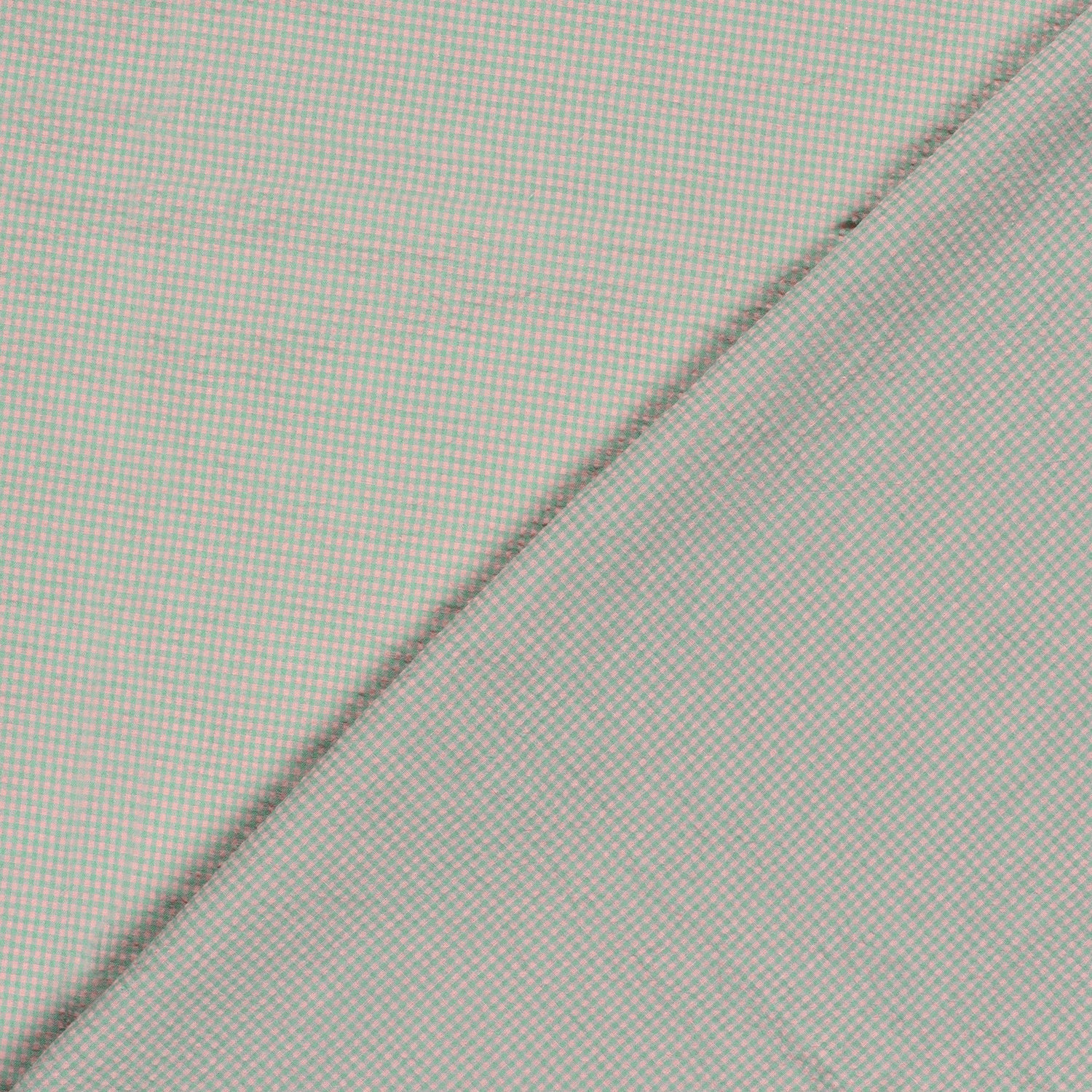 Close-up of a pink and green fabric with a fine micro-check pattern, folded diagonally across the frame.