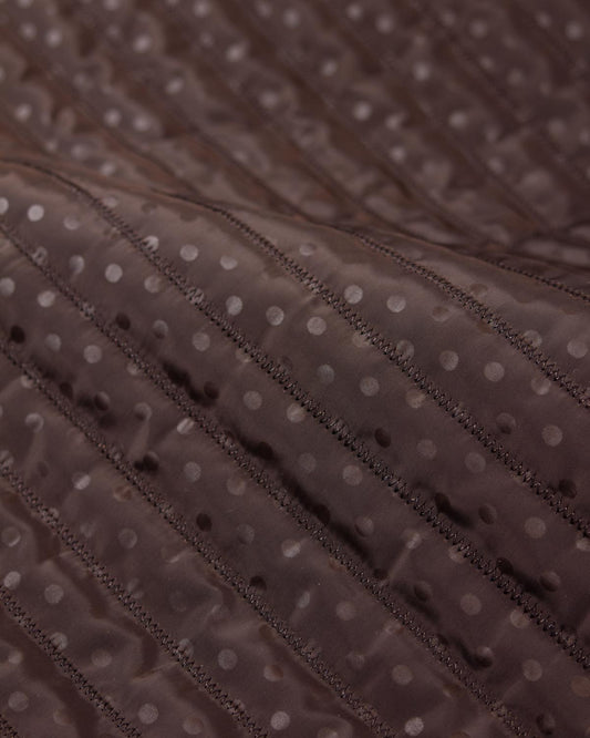 Chocolate brown showerproof quilted fabric with a white polka dot print and zigzag quilting over padded wadding.