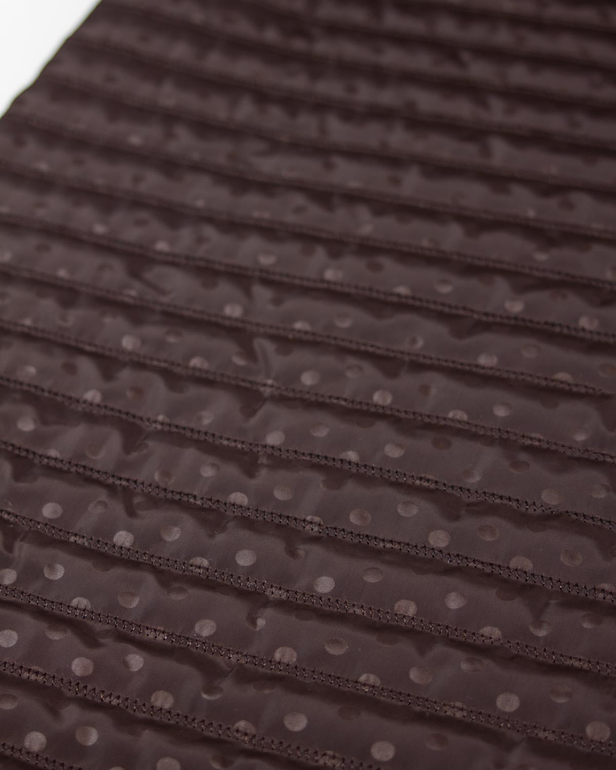 Chocolate brown showerproof quilted fabric with a white polka dot print and zigzag quilting over padded wadding.
