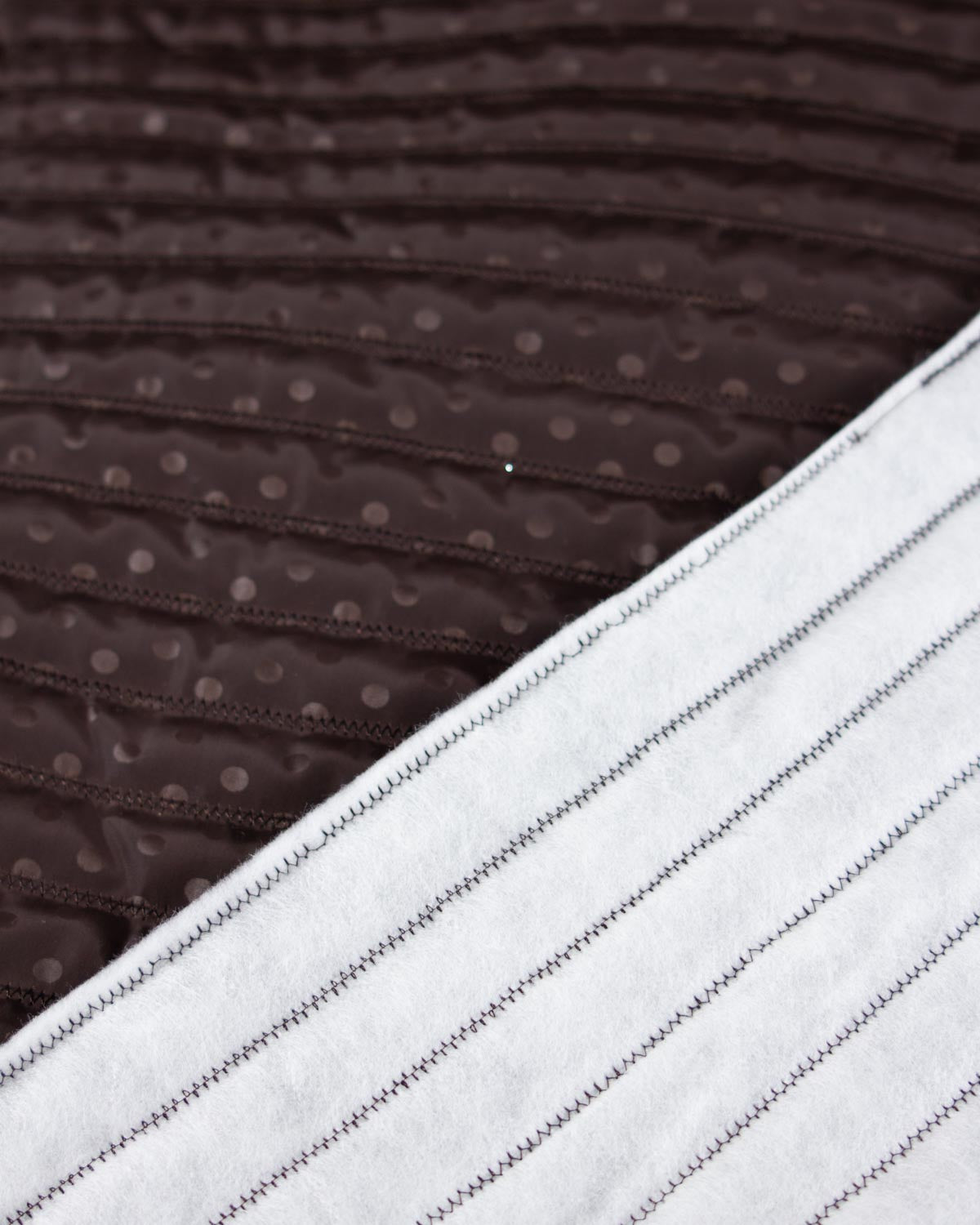 Chocolate brown showerproof quilted fabric with a white polka dot print and zigzag quilting over padded wadding.