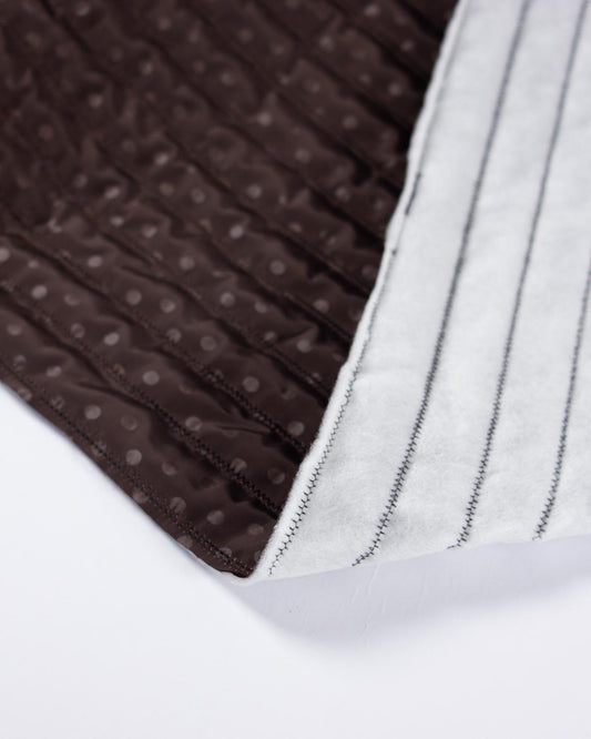 Chocolate brown showerproof quilted fabric with a white polka dot print and zigzag quilting over padded wadding.