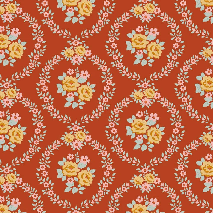 A repeating floral pattern on a warm rust-orange background, featuring yellow roses, pink blossoms, pale blue leaves, and white vine motifs arranged in oval frames.