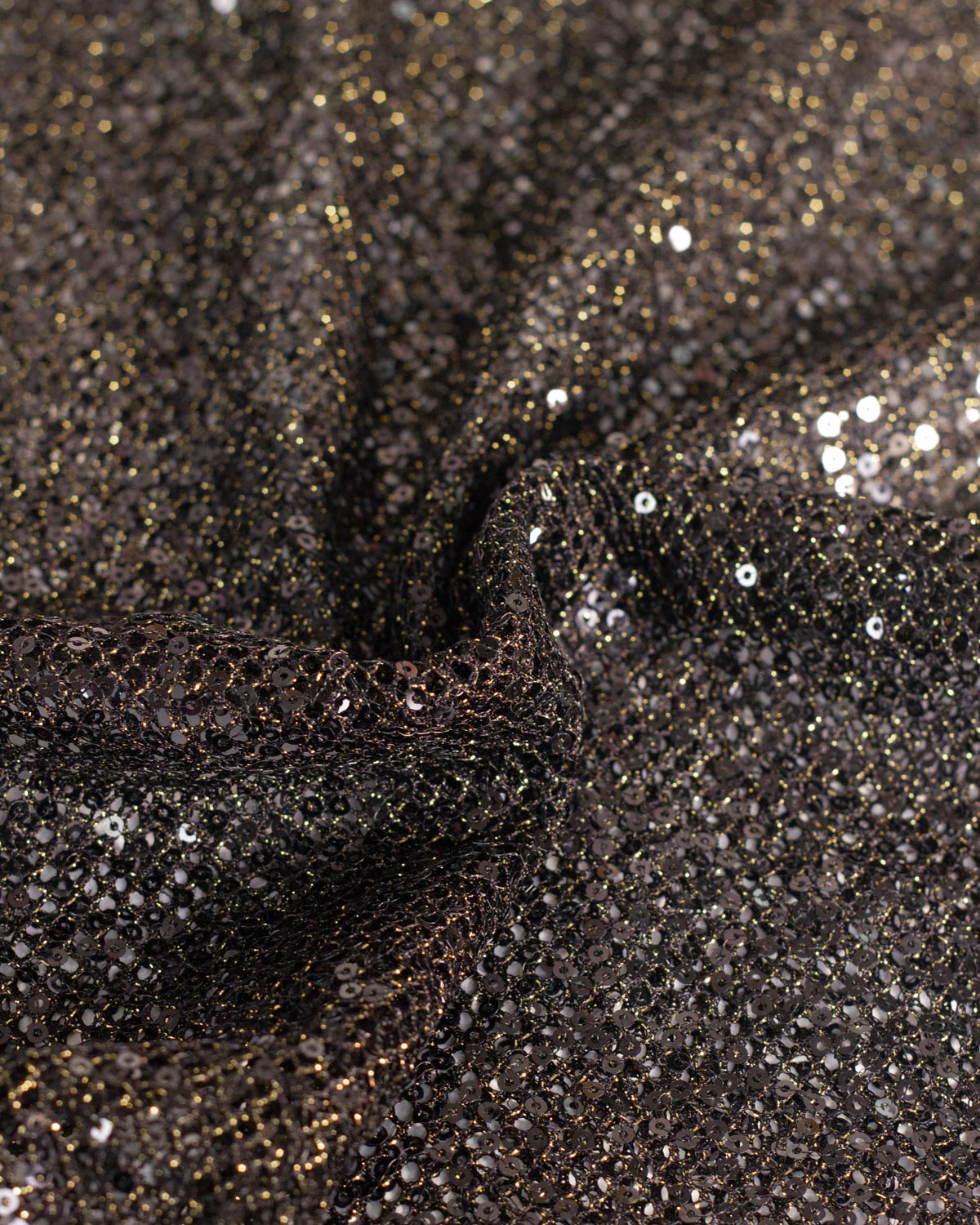 Close-up of a black fishnet tulle fabric with shimmering gold lurex and reflective black sequins, shown in a gathered drape.