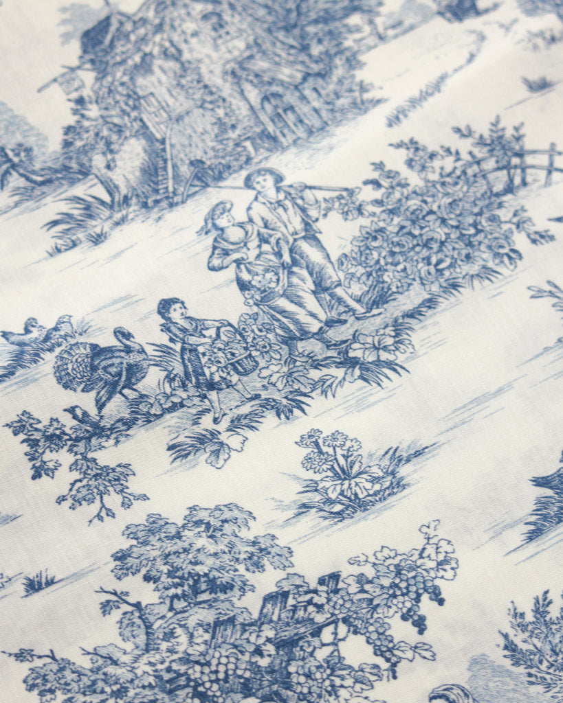 Blue and white toile pattern with people and nature  in blue on a white cotton curtain fabric 