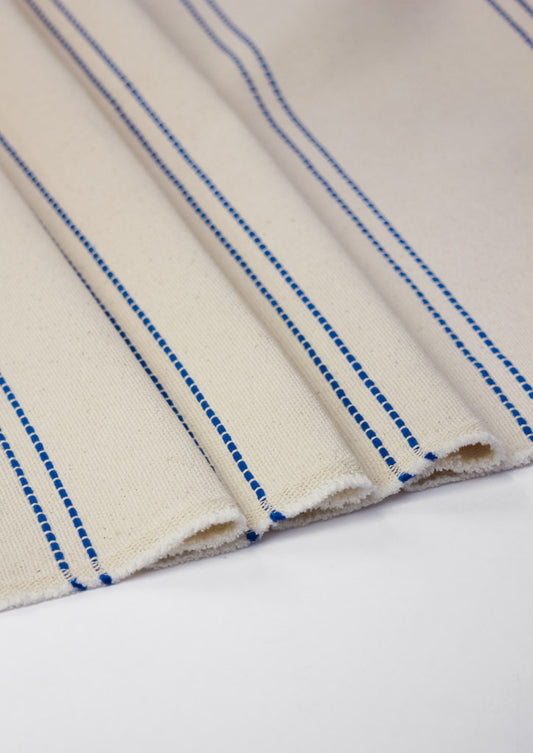Close-up of beige curtain fabric with blue stripes on a white background
