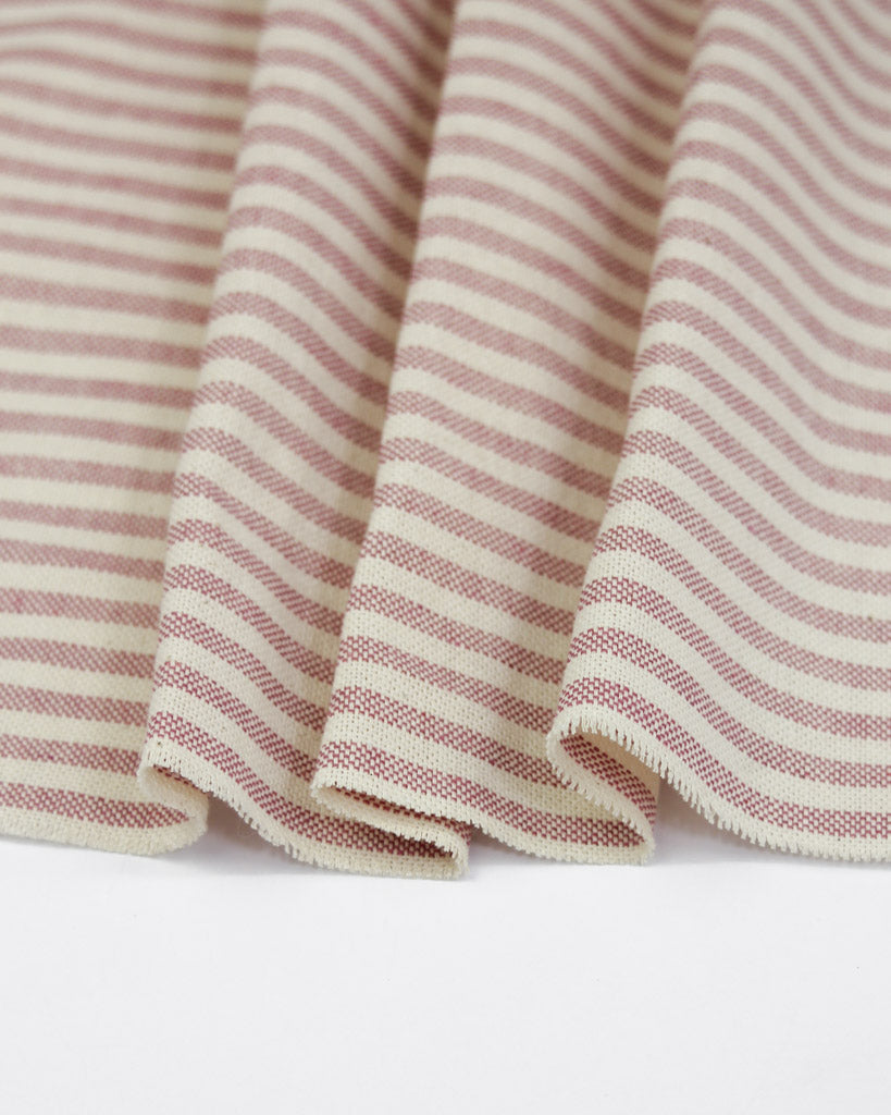 Close-up of pink and white striped curtain fabric on a neutral background