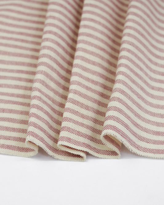 Close-up of pink and white striped curtain fabric on a neutral background