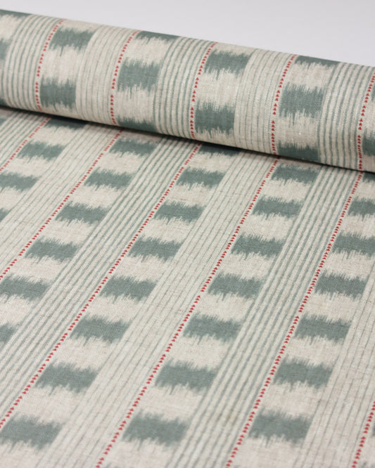 A close-up of linen upholstery fabric showing a repeating ikat-style design in muted sage green and off-white, with thin red dotted accent lines running vertically