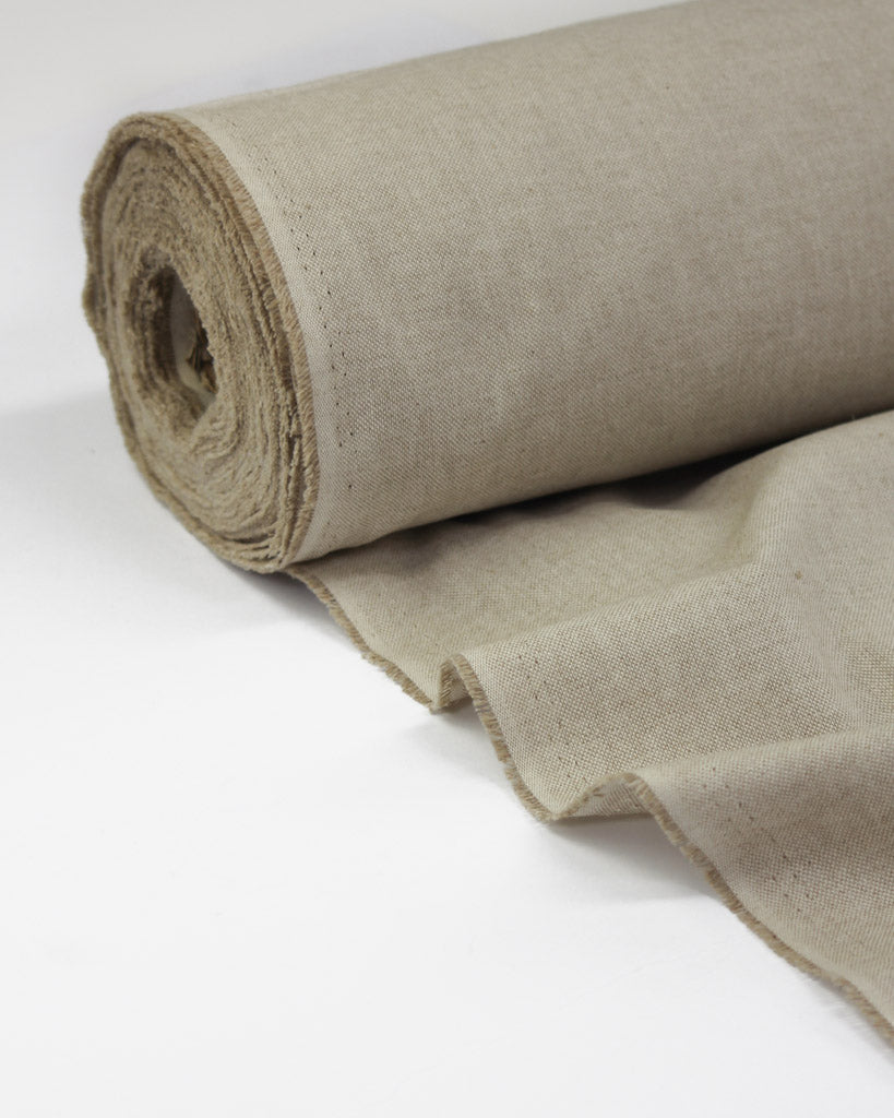 A roll of natural beige upholstery fabric with a visible woven texture, partially unrolled on a clean white surface.