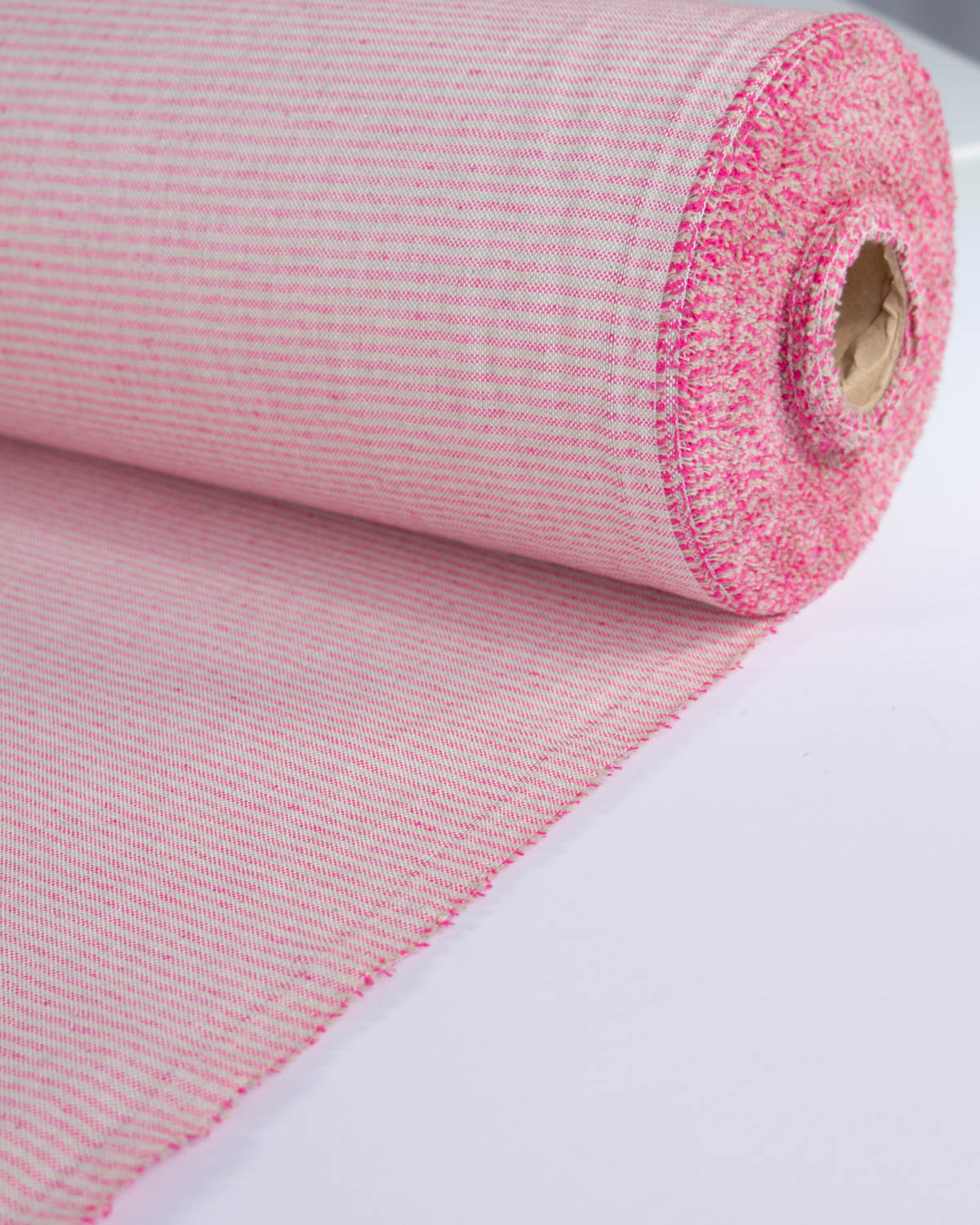 A roll of pink woven fabric with a fine textured pink stripe pattern, partially unrolled on a plain white surface.
